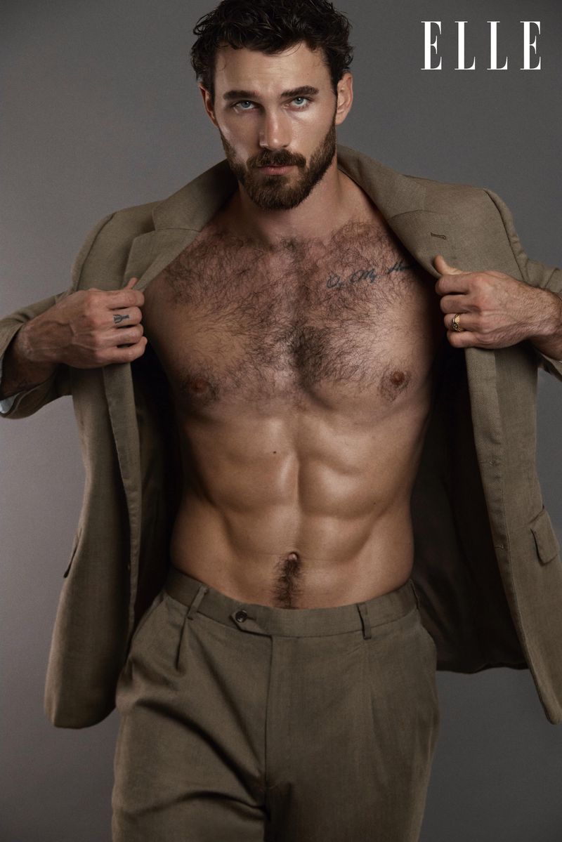 Portrait of a bearded man in a blazer and trousers with a bare torso in a studio, fashion editorial for Elle magazine.