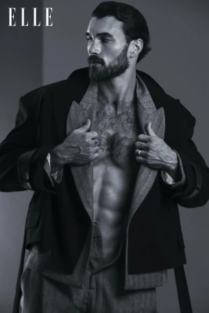 Michael Yerger posing in an open layered jacket revealing a bare chest against a studio backdrop for Elle China.