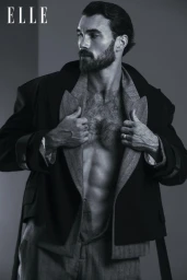 Michael Yerger posing in an open layered jacket revealing a bare chest against a studio backdrop for Elle China.