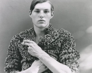 Portrait of a man wearing a leopard print jacket holding a cigarette, shot by Antonino Cafiero for Where We Were Before We Knew Ourselves