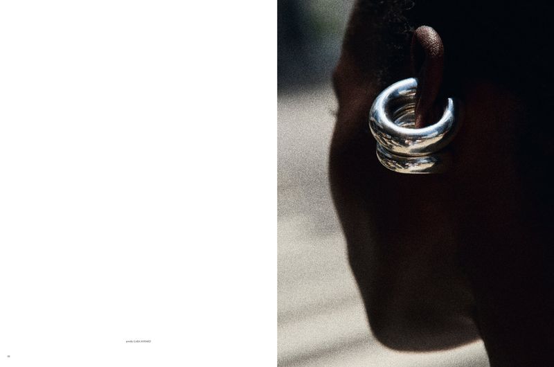 Close-up of a dark-skinned person wearing silver hoop earrings, showcasing beauty and fashion in an outdoor setting under natural light.