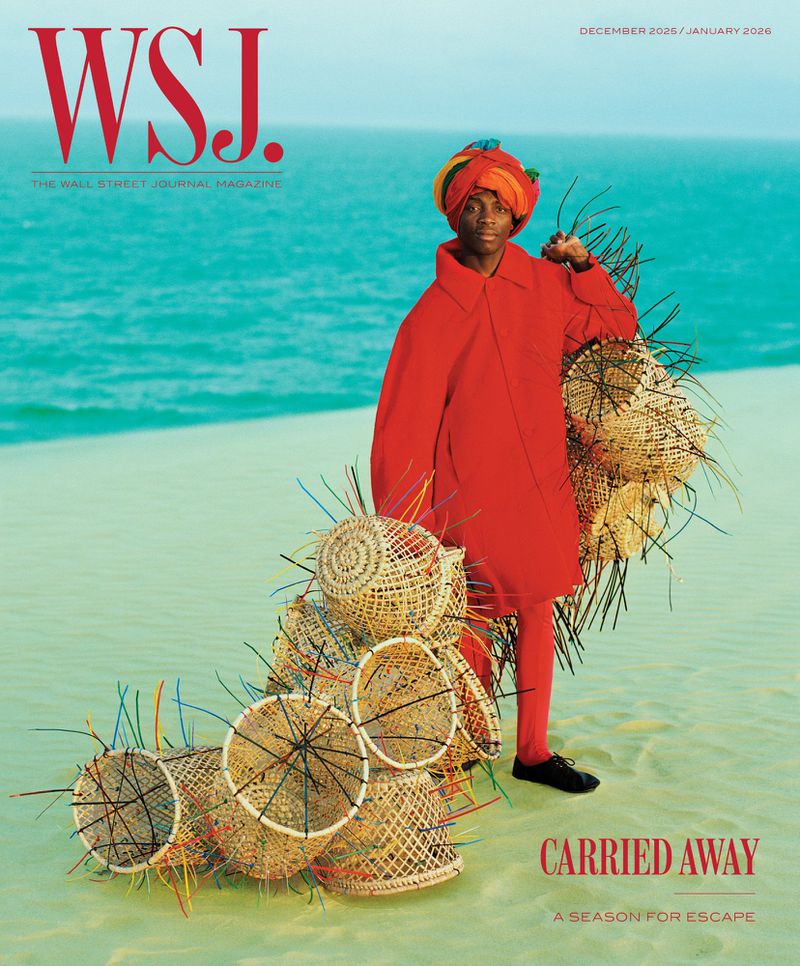 WSJ magazine cover featuring a person in bright red carrying weaved baskets on a beach with turquoise water and tan sand.