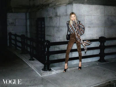 Model Baylee Winkel posing at night by an iron railing in a printed draped top and brown pants for Vogue Hong Kong.