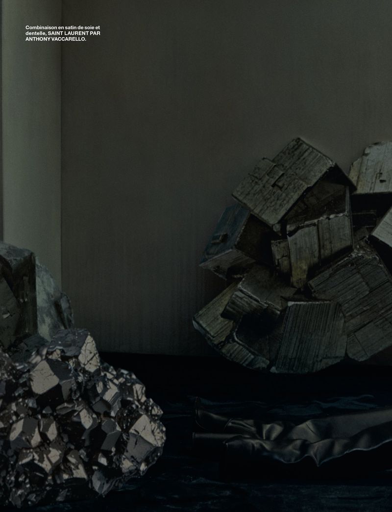 Dark still life composition of metallic pyrite stones with cubic formations, positioned on a black surface against a grey background.