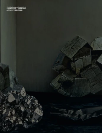 Dark still life composition of metallic pyrite stones with cubic formations, positioned on a black surface against a grey background.