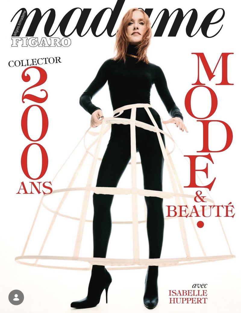 Magazine cover featuring Isabelle Huppert in a black bodysuit and heels, wearing a white pannier, with red and black text.