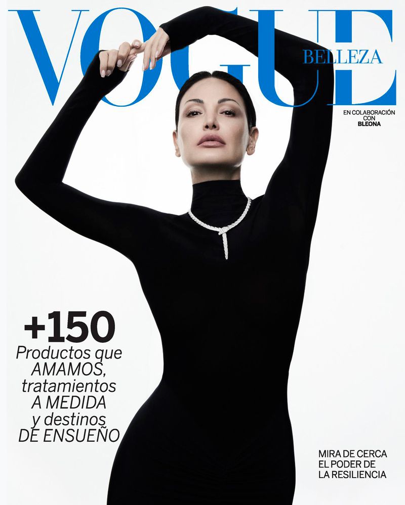Vogue magazine cover featuring a woman in a black turtleneck dress and diamond necklace, posing with raised arms against a white backdrop.