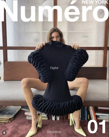 Model Nathali Fried holds a black ruffled dress while seated in pale yellow heels for Numéro New York Issue 01 digital cover.