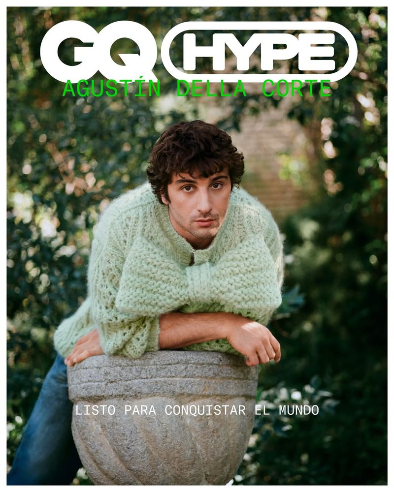 Magazine cover featuring Agustin Della Corte. He is wearing a light green sweater and leans against a stone planter outdoors in a garden setting.