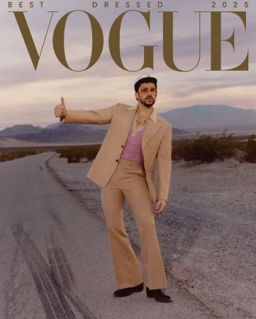 Vogue cover featuring a male model in a beige suit hitchhiking on a desert road, mountains in background, with 'Vogue' masthead above.