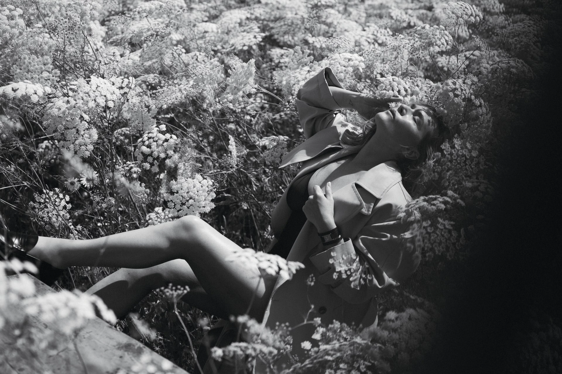 Kate Winslet reclining amidst a dense field of tall wildflowers for Vogue Australia, photographed in dramatic black and white.
