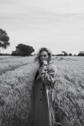 Kate Winslet wearing a trench coat standing in a wheat field in a black and white editorial photograph for Vogue Australia