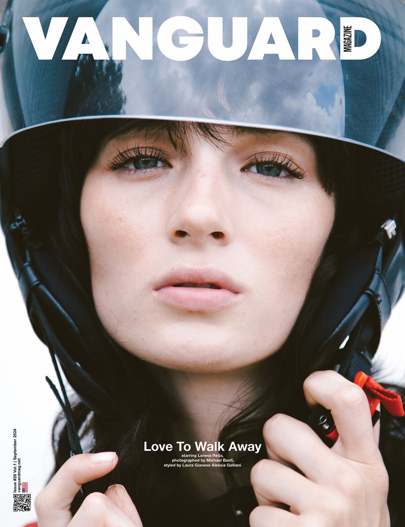 Magazine cover featuring a woman in a helmet, styled with muted makeup, against a blurred background, highlighting fashion and beauty elements.