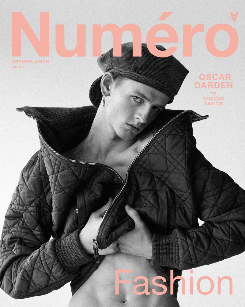 Magazine cover featuring a young adult male in a jacket and beret with pink text overlayed on a white background. Fashion editorial.