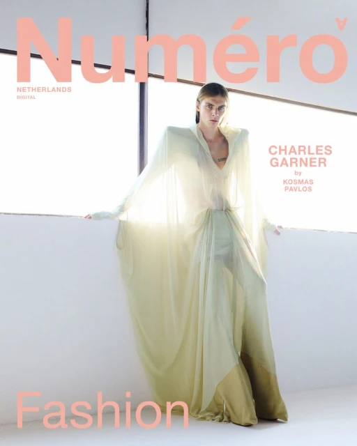 Fashion magazine cover featuring a slender adult woman in a long flowing dress, posing in front of a window with bright natural light.