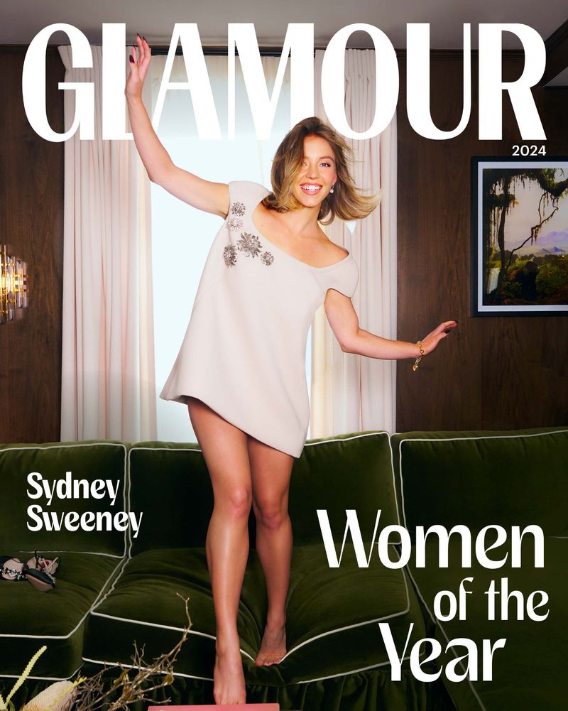 Glamour magazine cover featuring Sydney Sweeney in a white dress, posing on a green velvet couch under bright lighting, 'Women of the Year' issue.