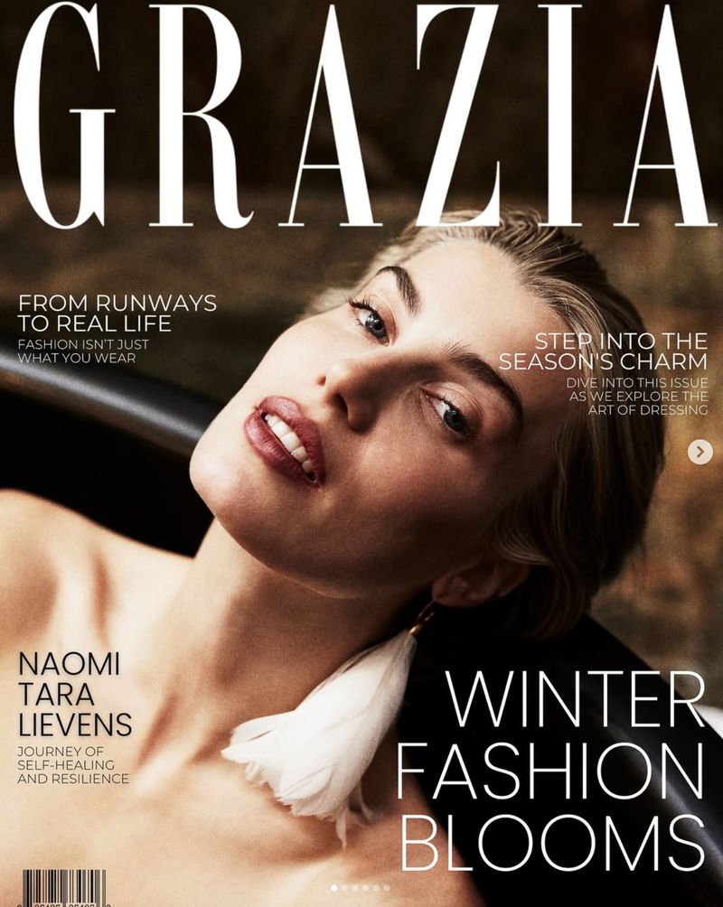 Fashion magazine cover featuring a light-skinned woman with blond hair and bare shoulders wearing feather earrings, posing in a dark bathtub.