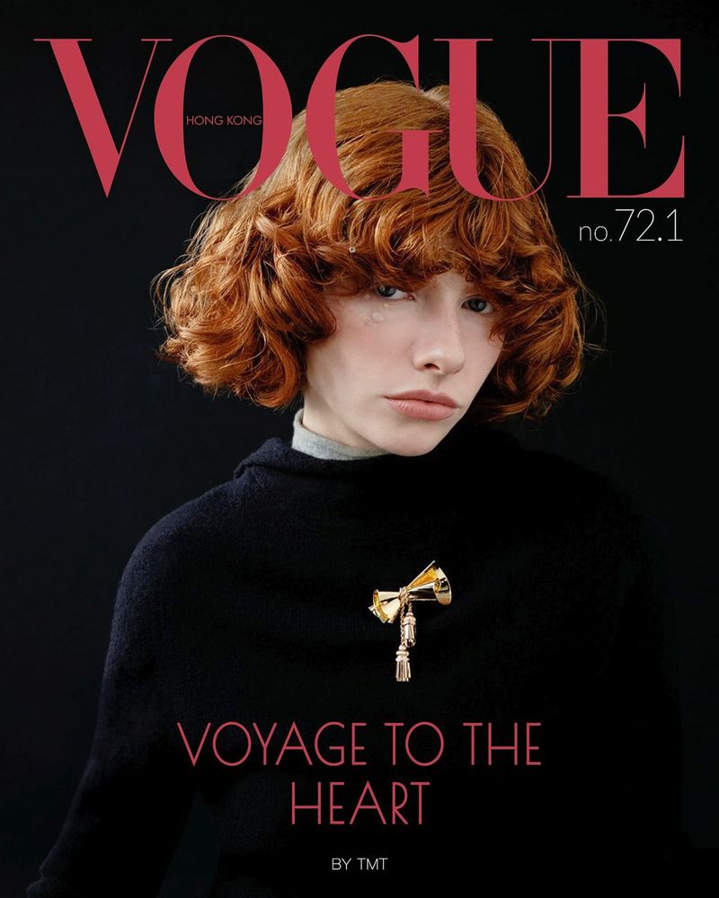 Vogue Hong Kong cover features a woman with curly orange hair wearing a black sweater and gold brooch against a dark background.