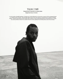Black and white portrait of a black man wearing a dark jacket in a minimal gallery interior for Love Want.