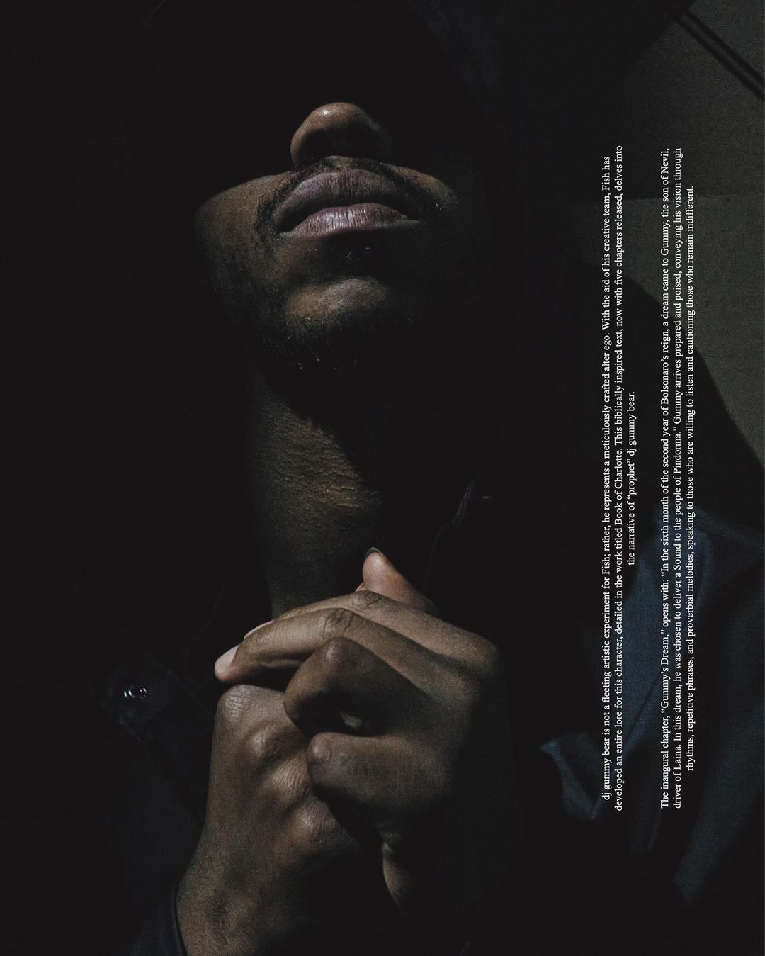 Close-up of Black adult male in a low key portrait. The man is looking up with hands clasped in an indoor environment.