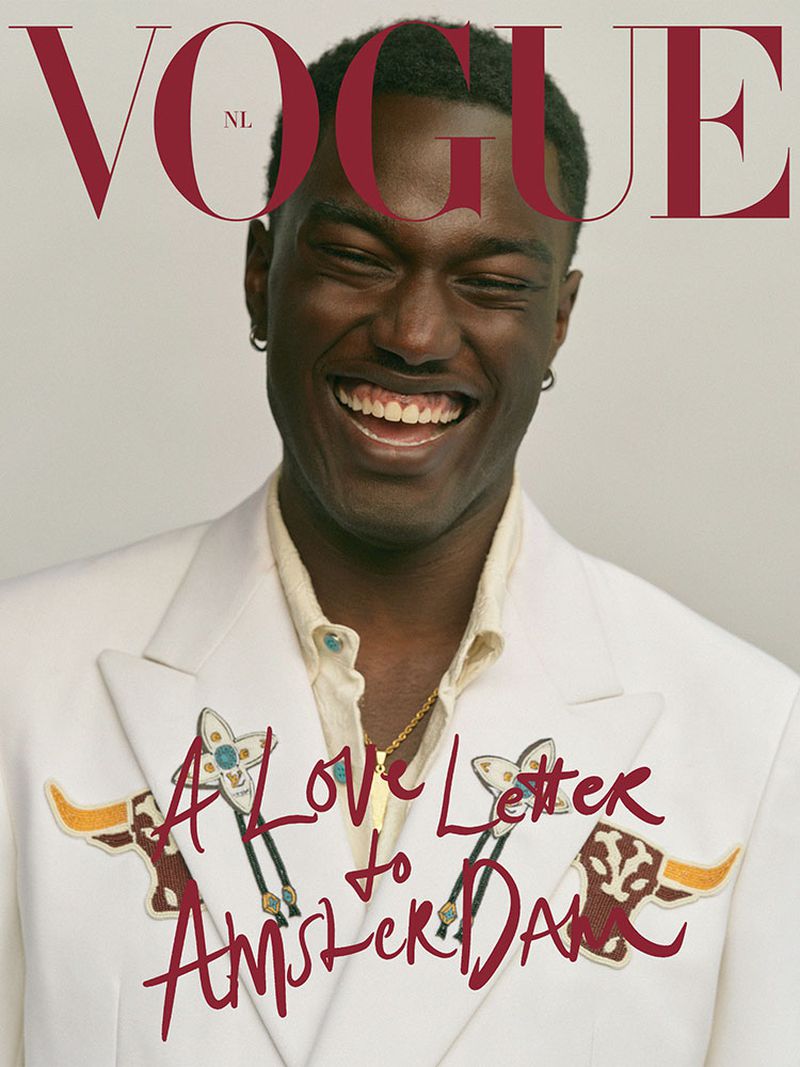 Vogue NL magazine cover featuring a smiling Black male model wearing a white suit with decorative bull embellishments. 