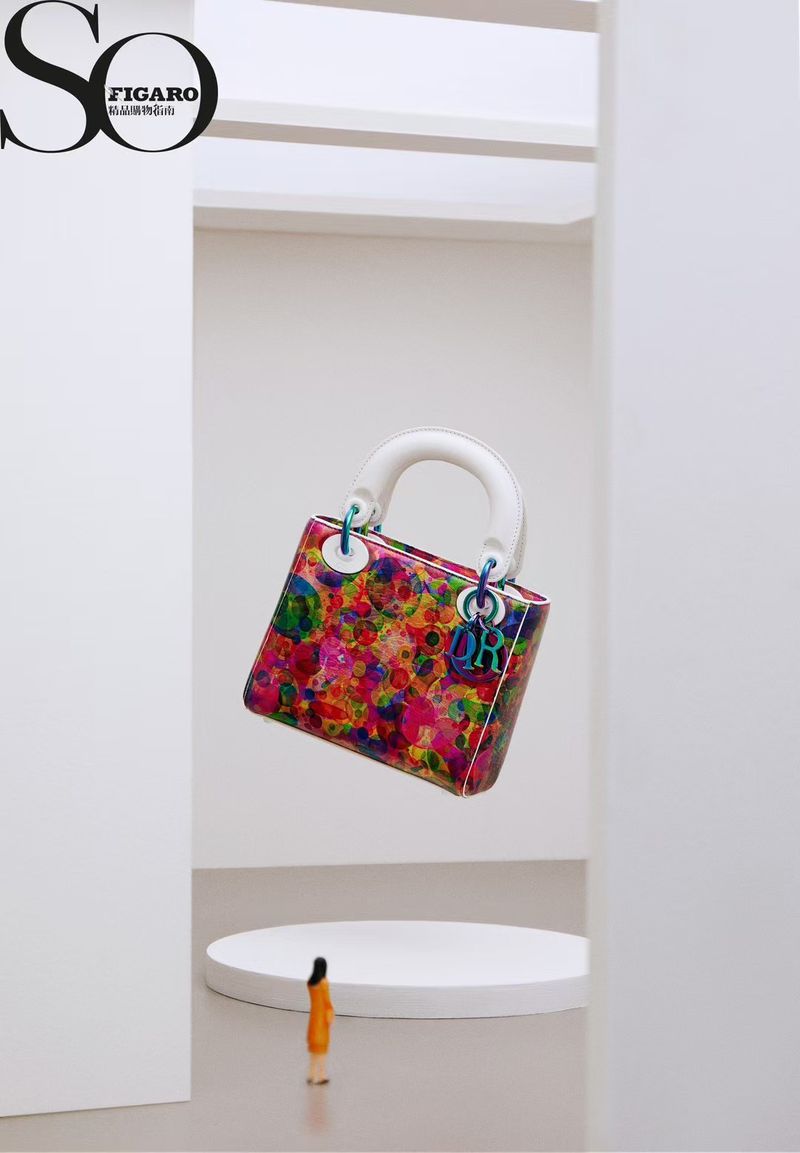 Colorful Dior handbag on a white pedestal, juxtaposed with a tiny model in an expansive white studio setting for a fashion editorial.