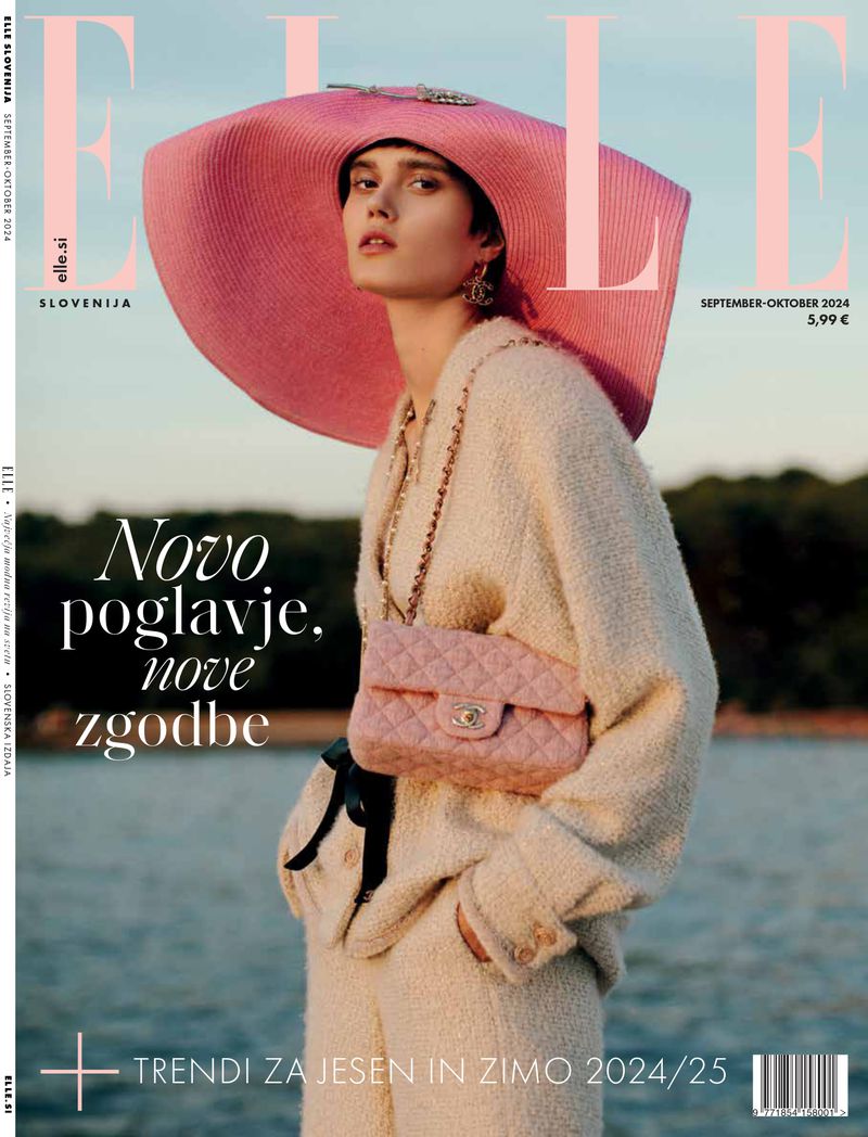 Fashion editorial cover featuring a model with a large pink hat and a quilted Chanel purse standing in front of a body of water.