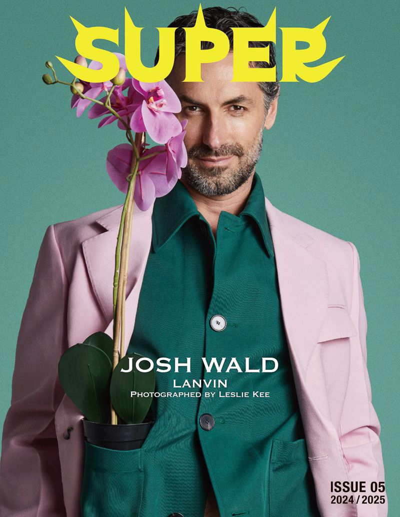 Magazine cover featuring a man in a pink blazer and green shirt holding a potted orchid against a light green background.