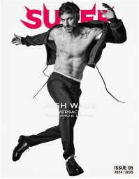 Model Josh Wald leaping in dark trousers and open jacket against a white background for Super Magazine