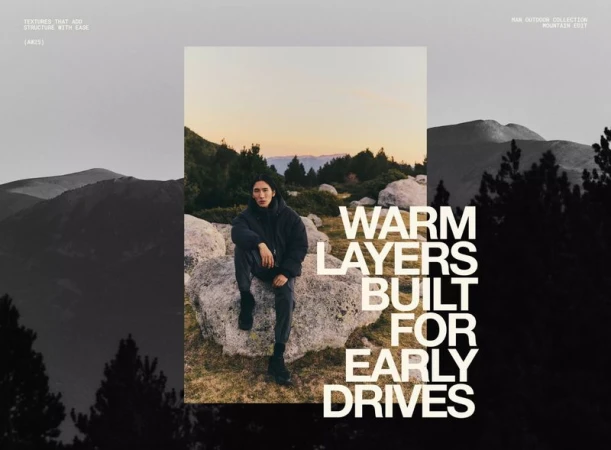 An adult male sits on a rock in an outdoor setting with a mountain backdrop, styled in a dark jacket and pants, under muted sunset lighting.