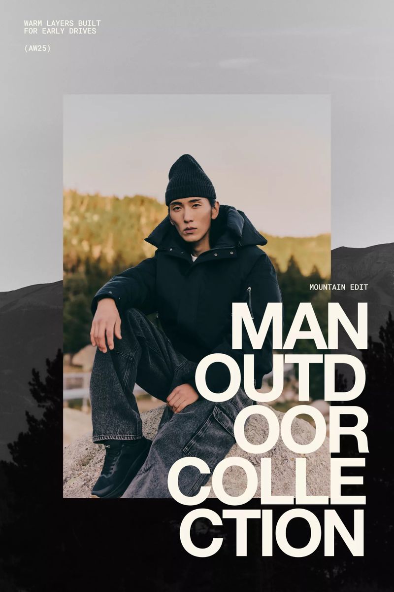 Asian male model wears a black puffer jacket and beanie, posing outdoors on a rock with a forest and mountain landscape in the background.
