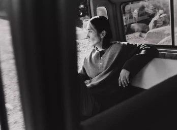 Model Hyuk Kim sitting in the back of a vehicle looking out the window in black and white for Lefties.