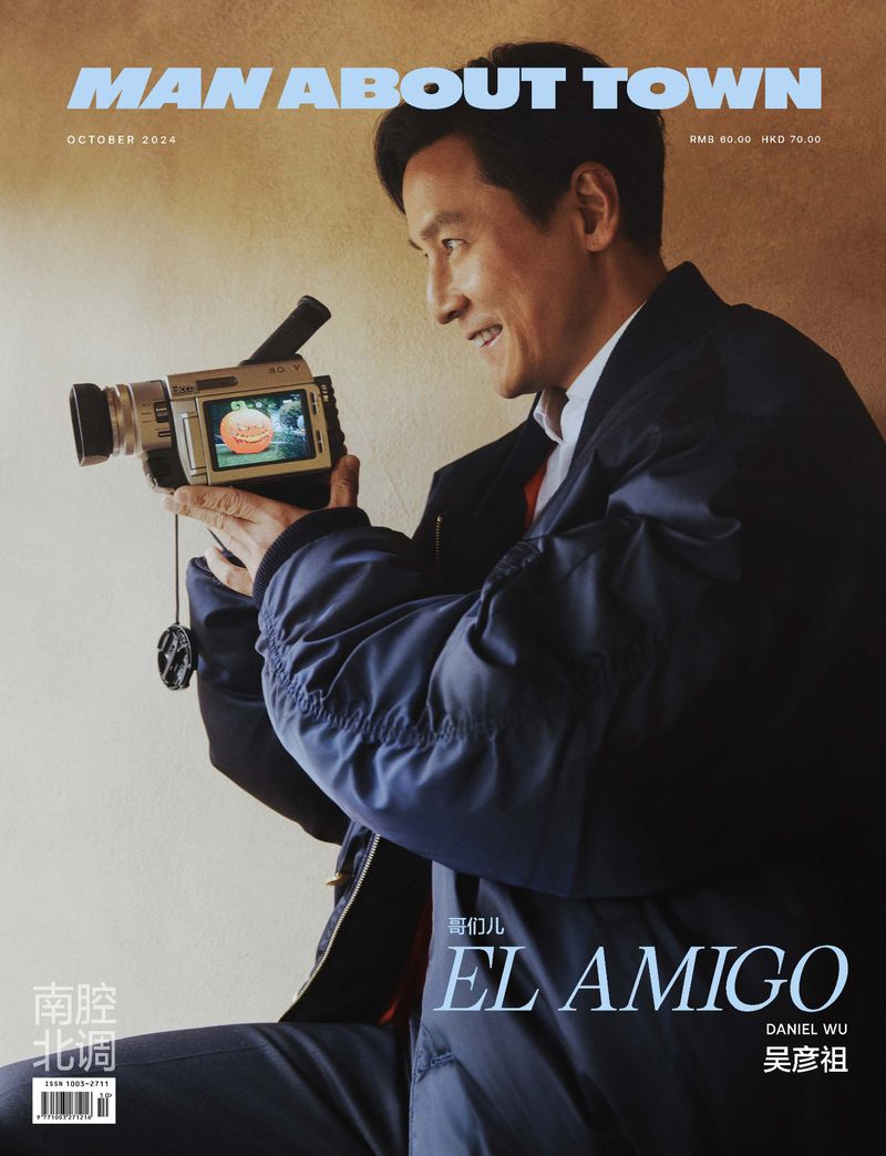 Magazine cover featuring Daniel Wu holding vintage video camera, wearing a blue jacket, photographed indoors with a tan backdrop.
