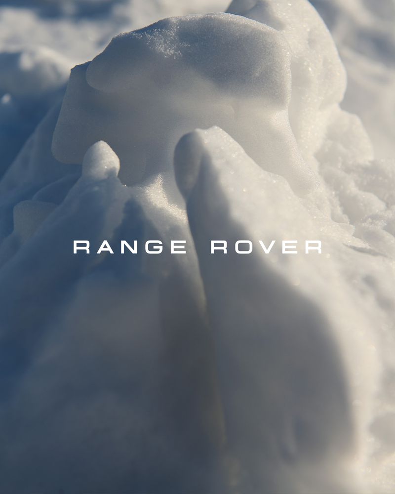 Close-up of a textured snow formation, white and blue tones, emphasizing natural patterns and cool winter ambiance. 'Range Rover' text overlay.