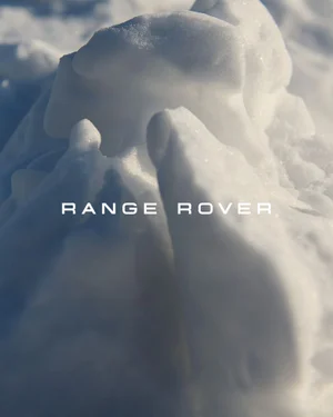 Close-up of sculpted white snow drifts and shadows with white Range Rover typography in the center.