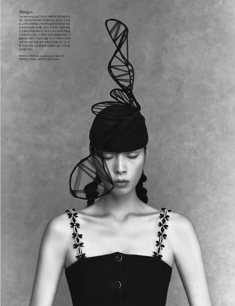 Editorial fashion portrait of an Asian woman wearing a black dress and decorative hat with DNA-inspired elements, shot in black and white.