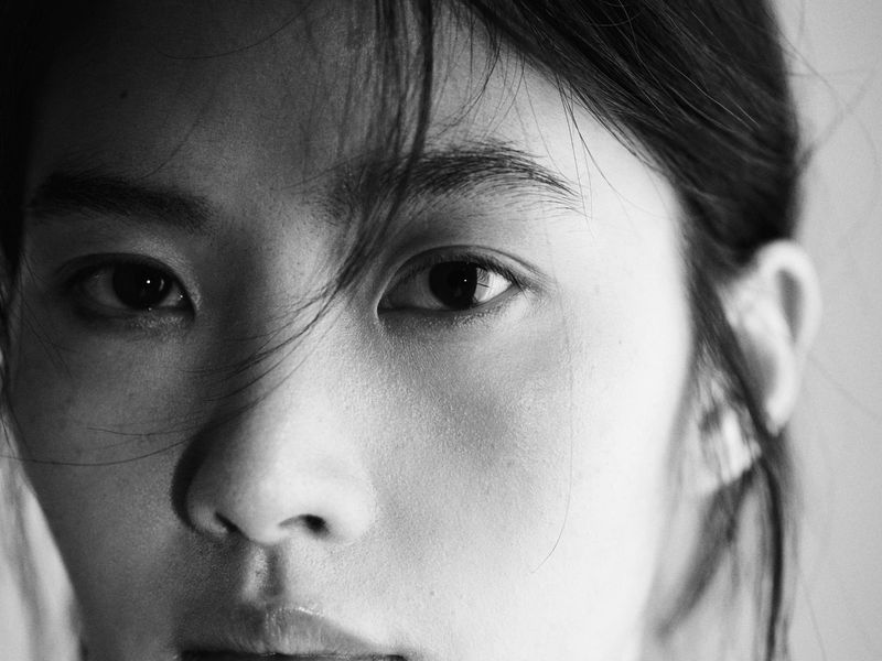 Close-up black and white portrait of a woman with loose hair falling across her face for Massimo Dutti