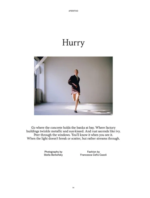 Fashion editorial shot of a woman in a brown suit running across a concrete floor with a large window providing natural light.