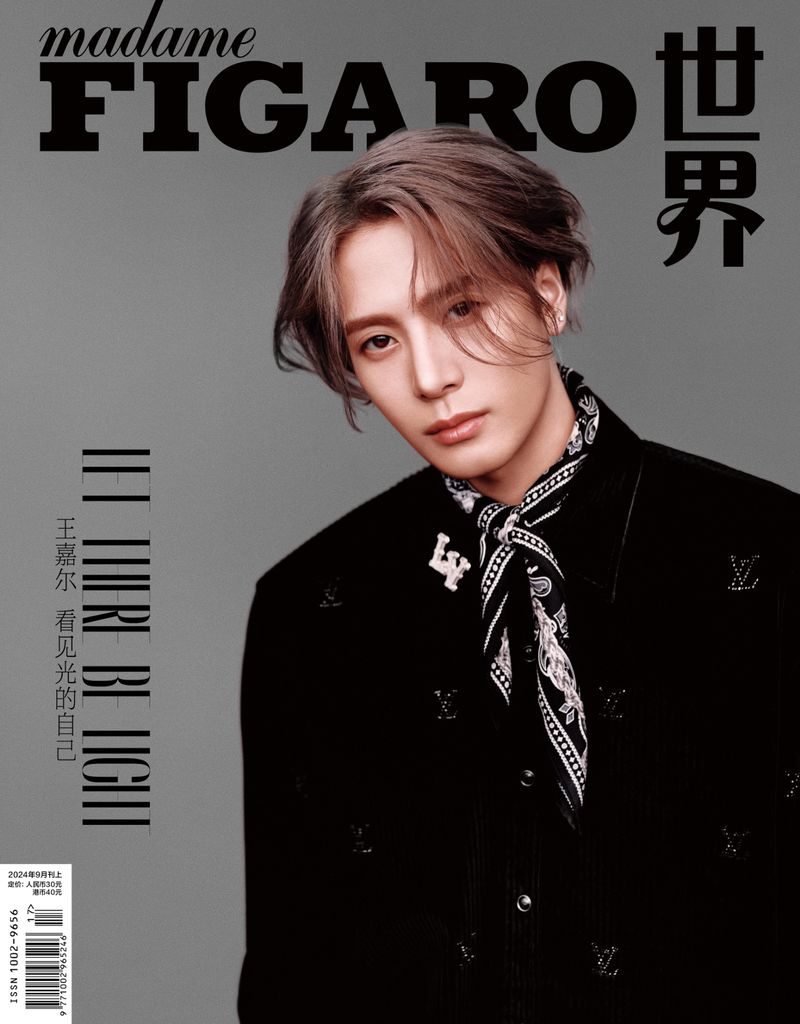 Magazine cover featuring an adult male with stylish brown hair, wearing a black jacket with LV logos, set against a grey backdrop.