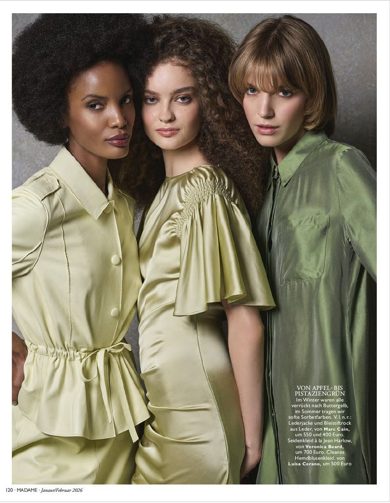 Three fashion models pose together in light green dresses against a neutral backdrop. They wear natural makeup and pose in a studio.