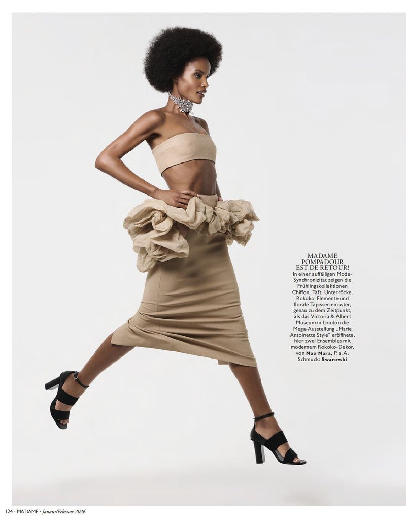 Fashion editorial shot of a woman in a beige two-piece outfit with a ruffled skirt, black heels, and a silver choker against a white background.