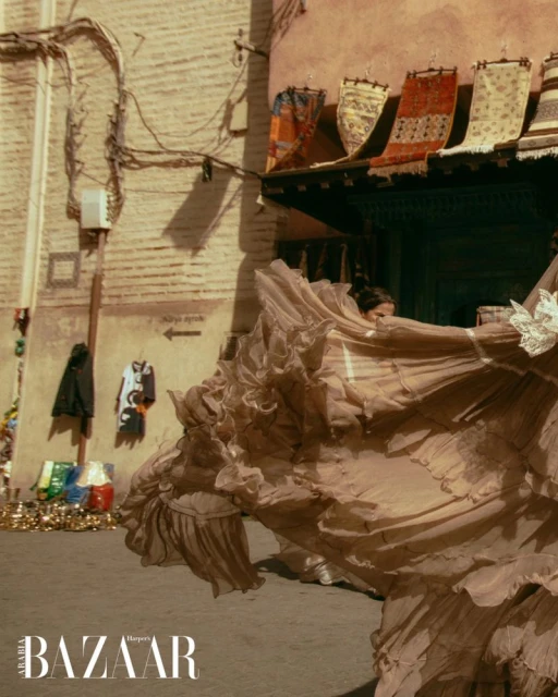Fashion editorial shot of a woman in a flowing dress in a Moroccan street, featuring architecture, textiles, and warm, natural light.