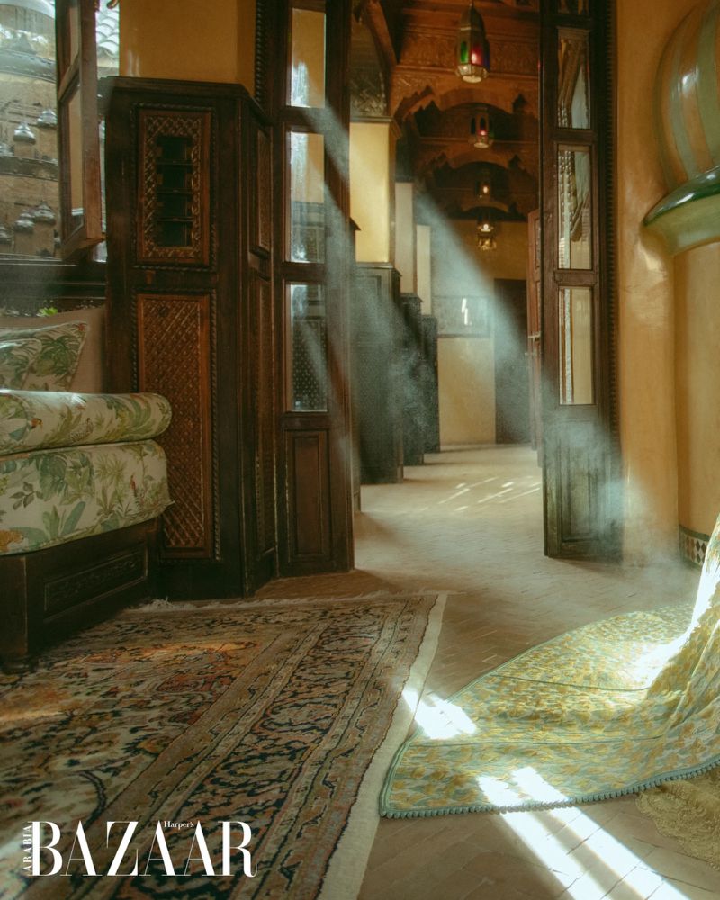 Ornately designed hotel hallway with patterned carpets and carved wood architectural details, illuminated by streams of natural light.