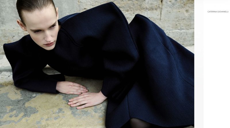 A fashion shot features a woman in a structured navy dress, posed on weathered stone, creating a blend of high fashion and rugged texture.