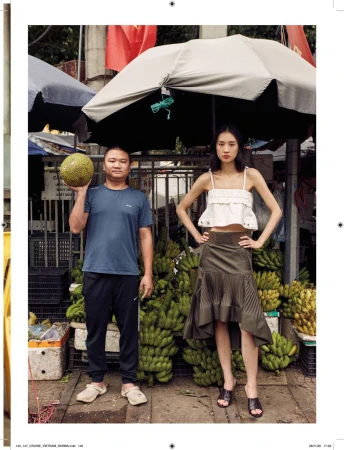 Man holding jackfruit and woman posing in front of banana stacks under umbrellas for Vietnam Delights editorial