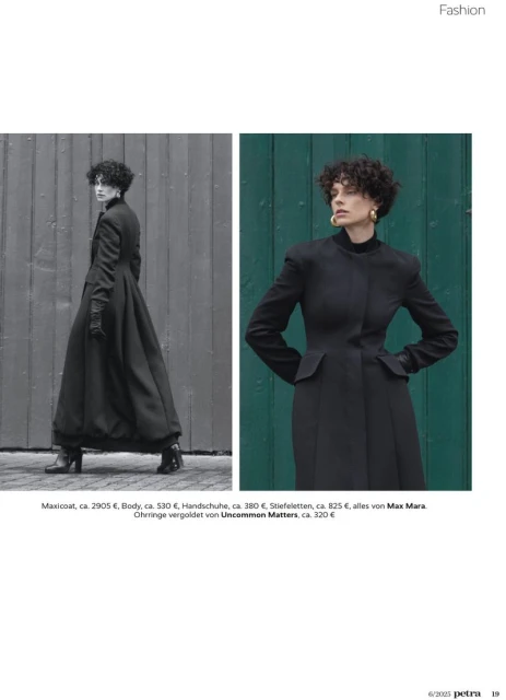 A fashion editorial presents a curly-haired woman in a long black coat against a muted wooden background and green wall, creating a minimalist aesthetic.