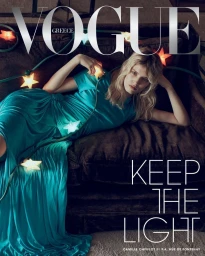 Model Camille Chifflot in a draped teal satin gown reclining on a dark couch adorned with glowing star string lights for Vogue Greece.