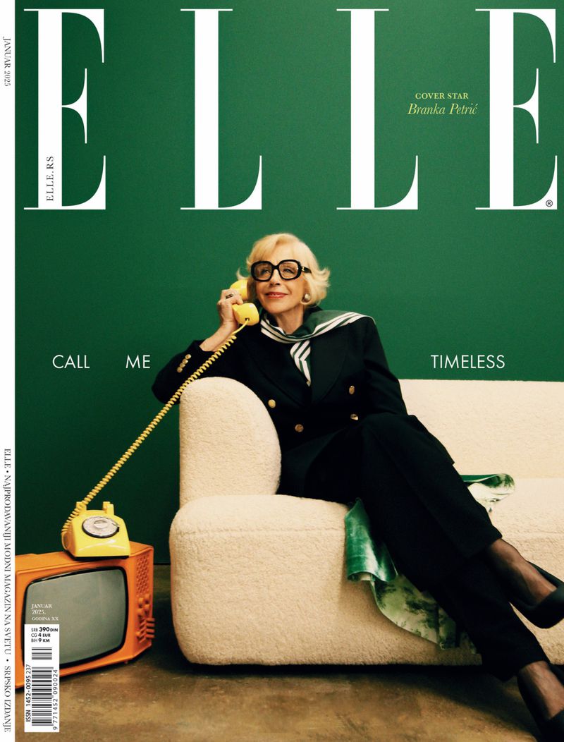 Elderly woman with glasses poses with yellow retro phone on a couch, set against a green background, for an Elle magazine cover.