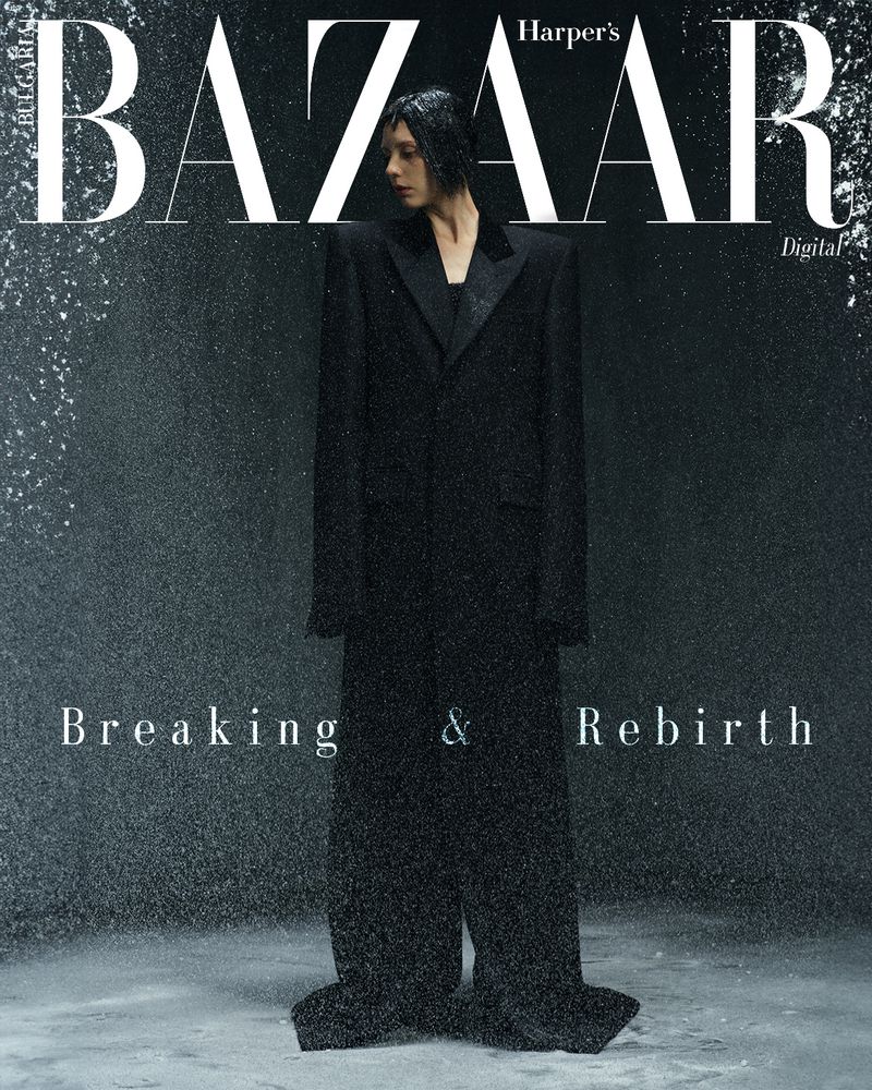 Fashion editorial cover of Harper's Bazaar featuring a woman in an oversized black suit in a wet environment, with a dark moody color palette.