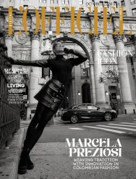 Monochrome magazine cover featuring a woman posing dynamically against a classic stone building facade with a car in the street.